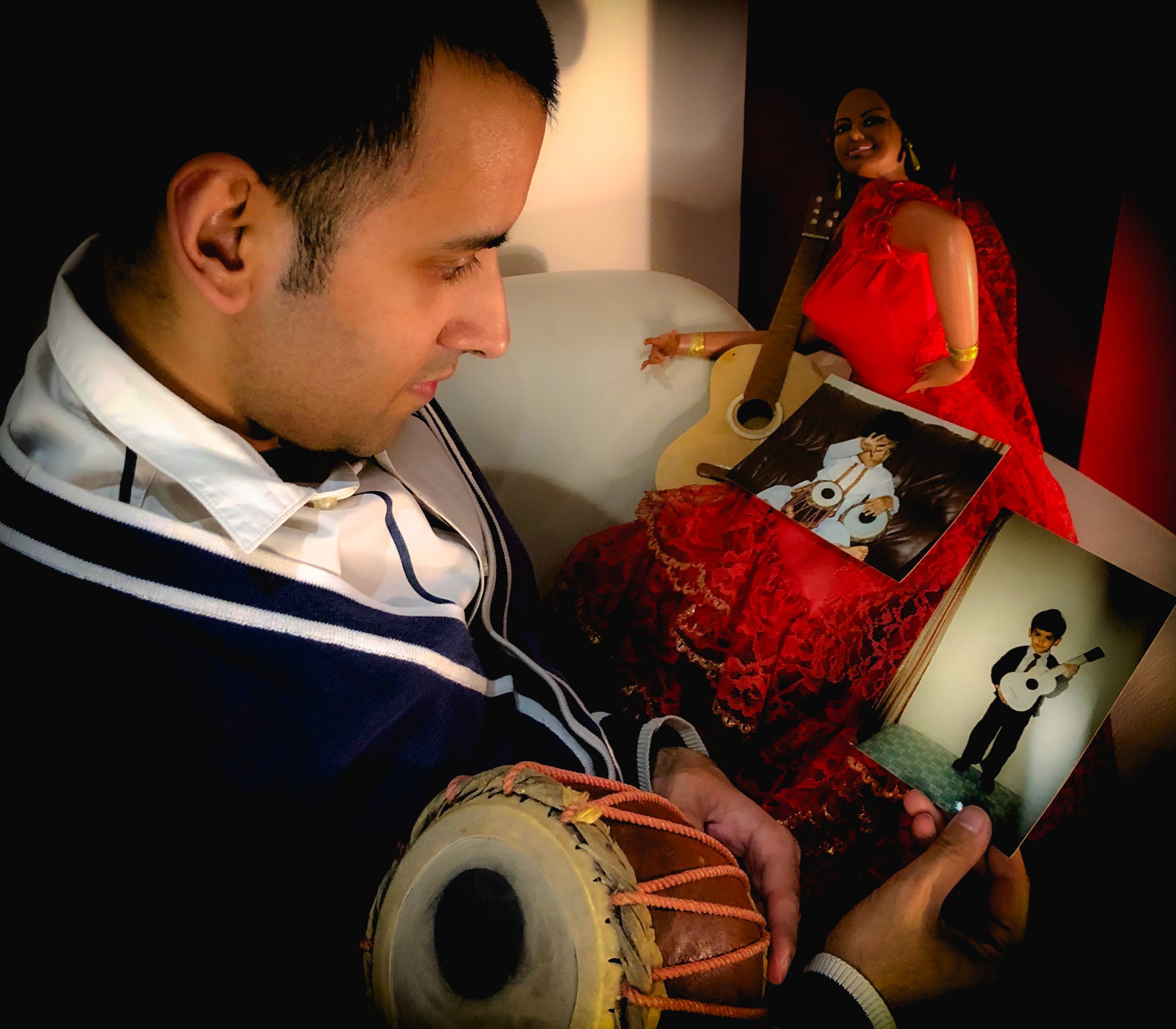 Reminiscing musical instrument memories, childhood memories and old photographs, with a ukulele, tabla (Indian drum) and doll wearing a long red dress, holding a guitar